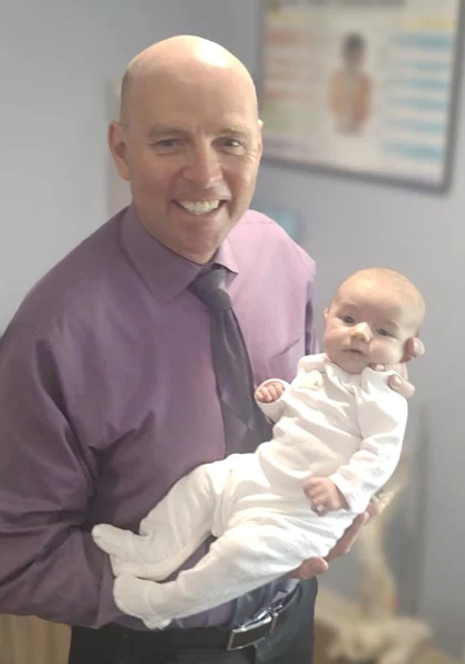 Dr. Eric Christie smiling while holding a baby at the office