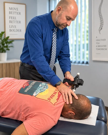 Dr. Eric Christie using a handheld adjusting instrument while treating a patient