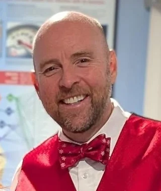 Dr. Eric Christie smiling at the office in a red waistcoat and bow tie